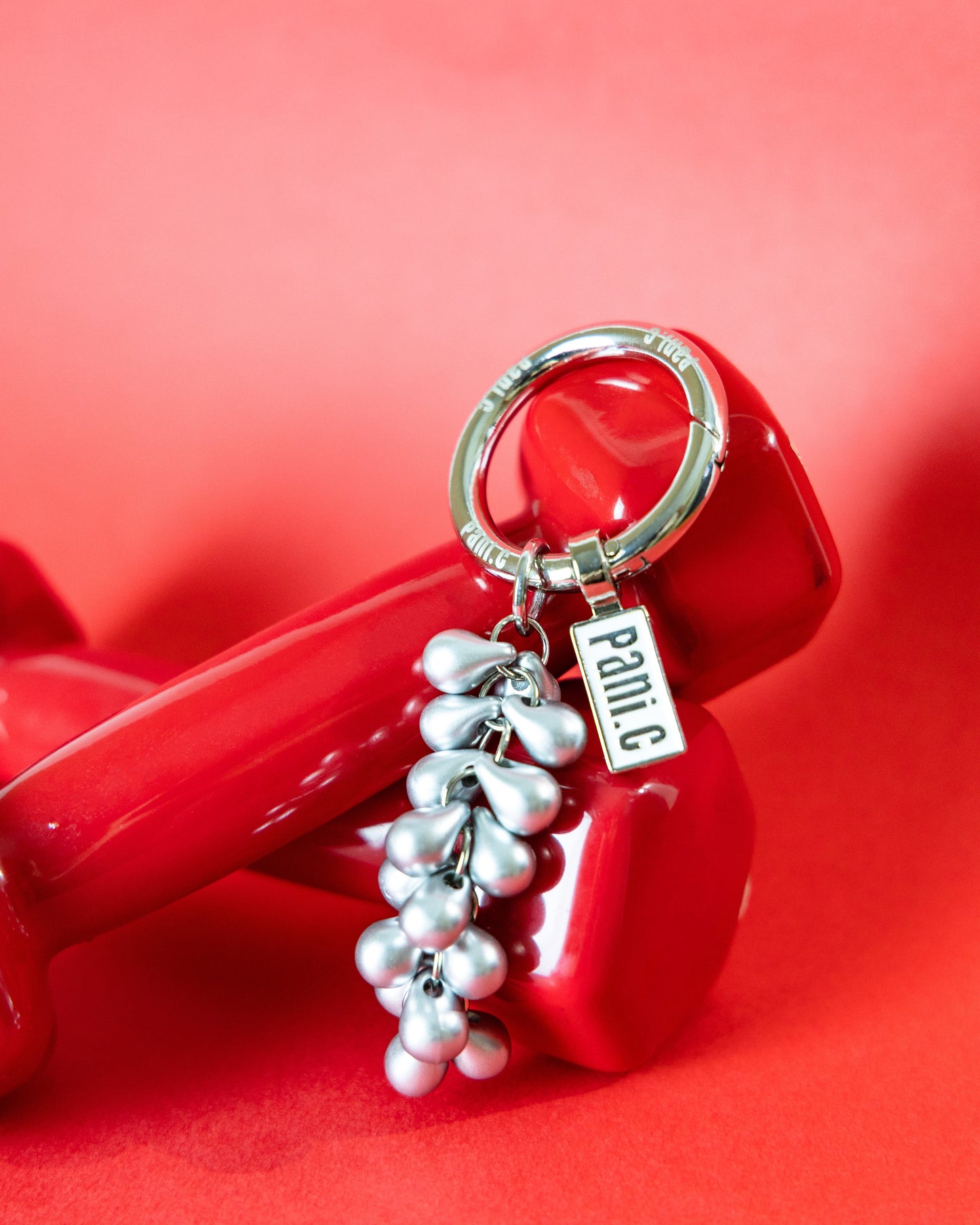 Keychain with silver grape shape charm on a red background